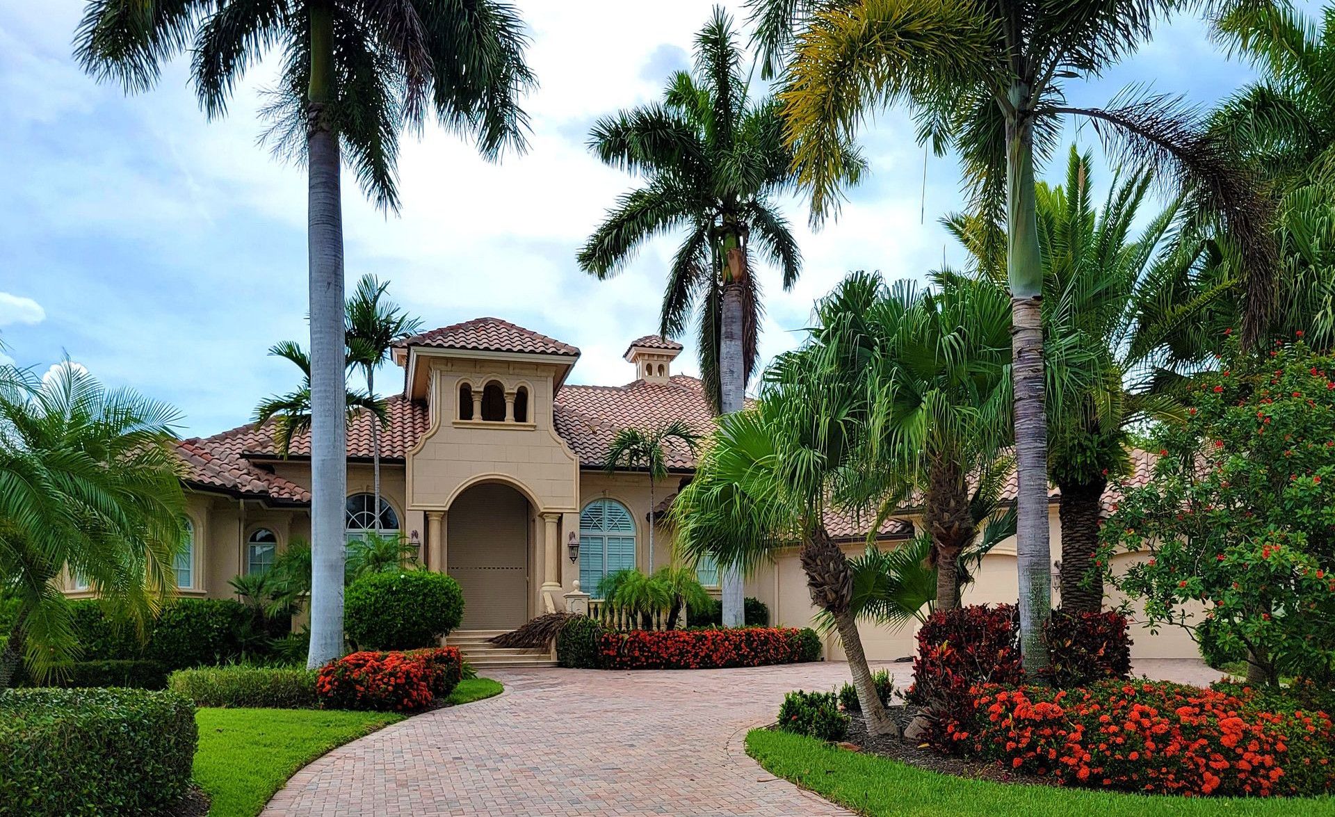 Elegant mansion with lush palm trees and landscaped garden, perfect for luxury living.